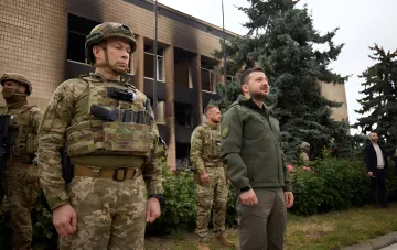 Президент Украины Зеленский с военнослужащими на фоне повреждённого здания в контексте Харьковской наступательной операции 2022 года