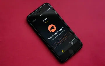 Smartphone showing an air raid alert app for Kyiv — siren icon and instruction to go to shelter
