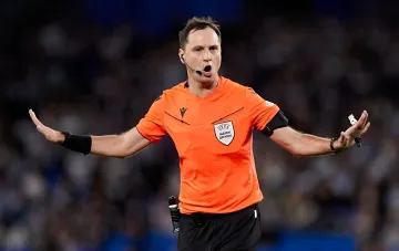 Schiedsrichter Serhij Balakin in orangefarbener UEFA Match Official-Kleidung, der bei einem Champions-League-Spiel pfeift