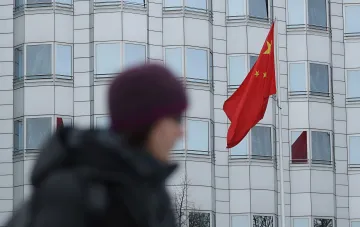 Китайський прапор на тлі сучасного промислового будівництва в Європі — символ конкуренції, що загрожує робочим місцям у ЄС