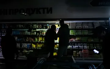 Покупатели выбирают продукты на освещённых полках супермаркета в условиях блекаута в Киеве
