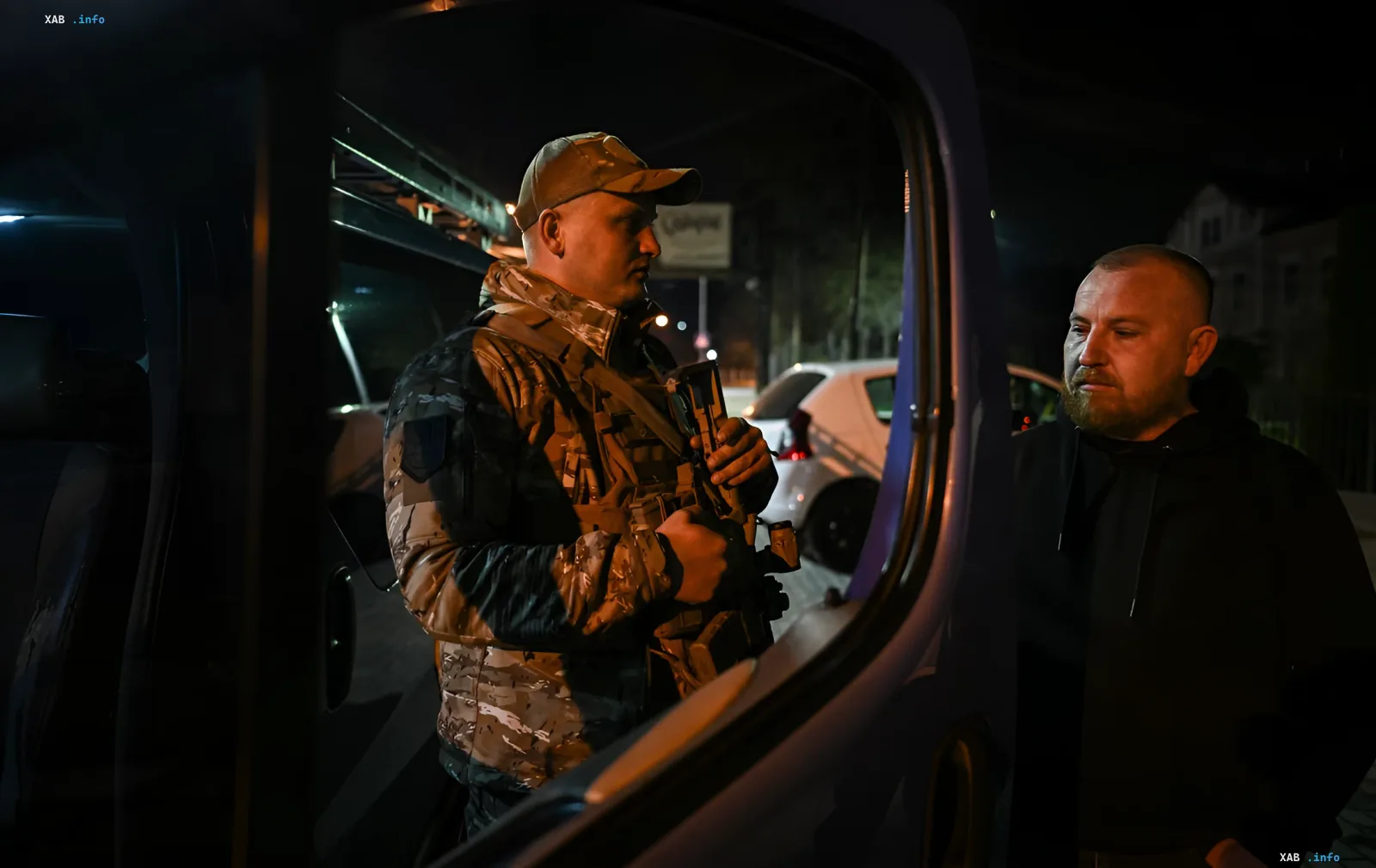 Збройний військовослужбовець у камуфляжі та чоловік у нічному місті під час комендантської години в Києві