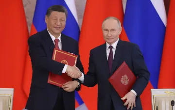Си Цзиньпин и Владимир Путин на фоне флагов Китая и России подписывают документы о сотрудничестве, скрывающем поставки химикатов для дронов-камикадзе