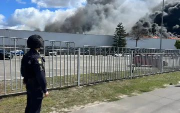 Пожеба на тютюновій фабриці BAT в Прилуках після удару БПЛА, поліцейський на тлі диму