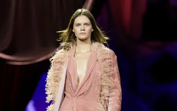 Модель в розовом костюме с бахромой на подиуме во время показа 59-го сезона Ukrainian Fashion Week