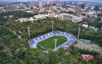 Leeres Dynamo-Stadion in Kiew mit blauen Tribünen und Clubnamen vor dem Stadtpark und der Skyline der Hauptstadt