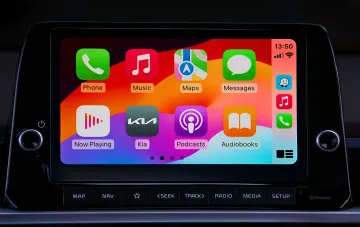 Экран Apple CarPlay с иконкой ИИ-ассистента Claude от Anthropic на фоне интерфейса Kia