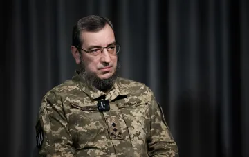 Офицер ВСУ в камуфляжной форме с нашивками ЗСУ и микрофоном RODE на фоне тёмного занавеса — заявление ГУР об испытаниях Россией баллистических ракет дальностью 800 км