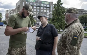 Сотрудники ТЦК проверяют документы у мужчины на улице в Днепре