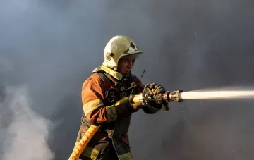 Пожарный тушит последствия попадания российского дрона в девятиэтажный жилой дом в Днепровском районе Киева