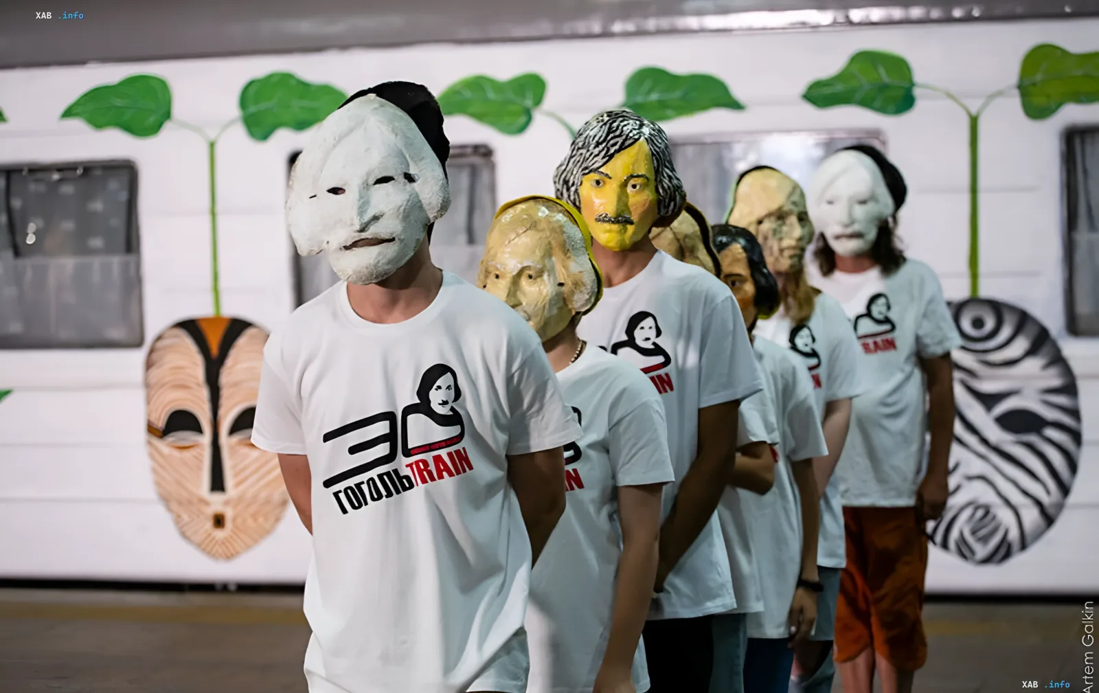 Участники перформанса «ГогольFest» в масках и футболках с логотипом «30 Гоголь Train» на фоне вагона с рисунками масок