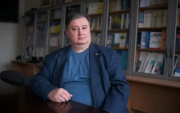 Эксперт НАН Украины в кабинете с книжными полками, комментирующий новые факторы эмиграции и исчерпанный пик миграции
