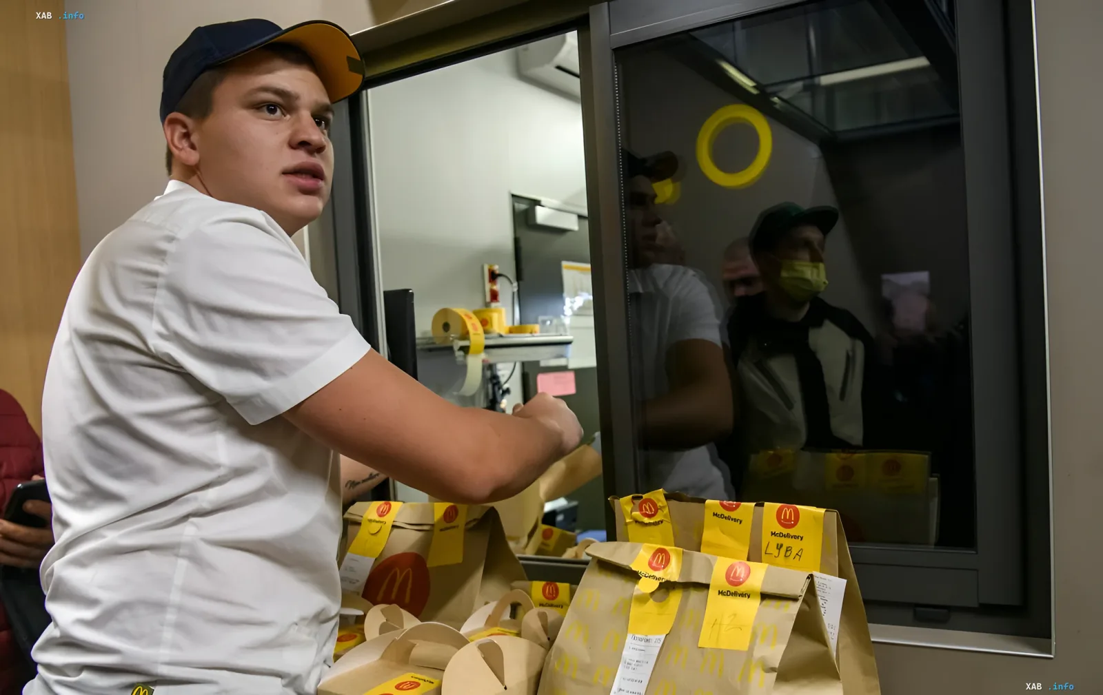 Сотрудник McDonald's в Украине упаковывает заказы McDelivery у окна выдачи, работа ресторана продолжается в обычном режиме
