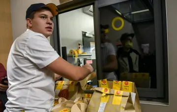 Сотрудник McDonald's в Украине упаковывает заказы McDelivery у окна выдачи, работа ресторана продолжается в обычном режиме
