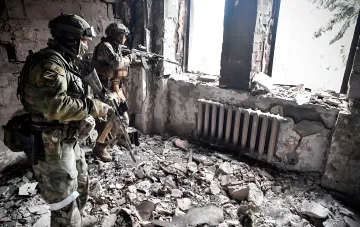 Боевые действия в зоне конфликта: военные с автоматическим оружием в разрушенном здании на фоне сообщений о потерях армии РФ