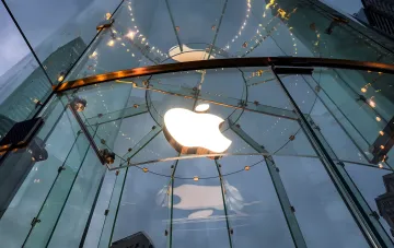 Подсвеченный логотип Apple в стеклянном куполе магазина на фоне закатного неба — анонс iOS 27 и iPadOS 27 с новой Siri на базе Gemini