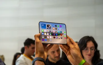Customer examining a new iPhone 18 with iOS interface at an event ahead of the September 25 launch in Ukraine
