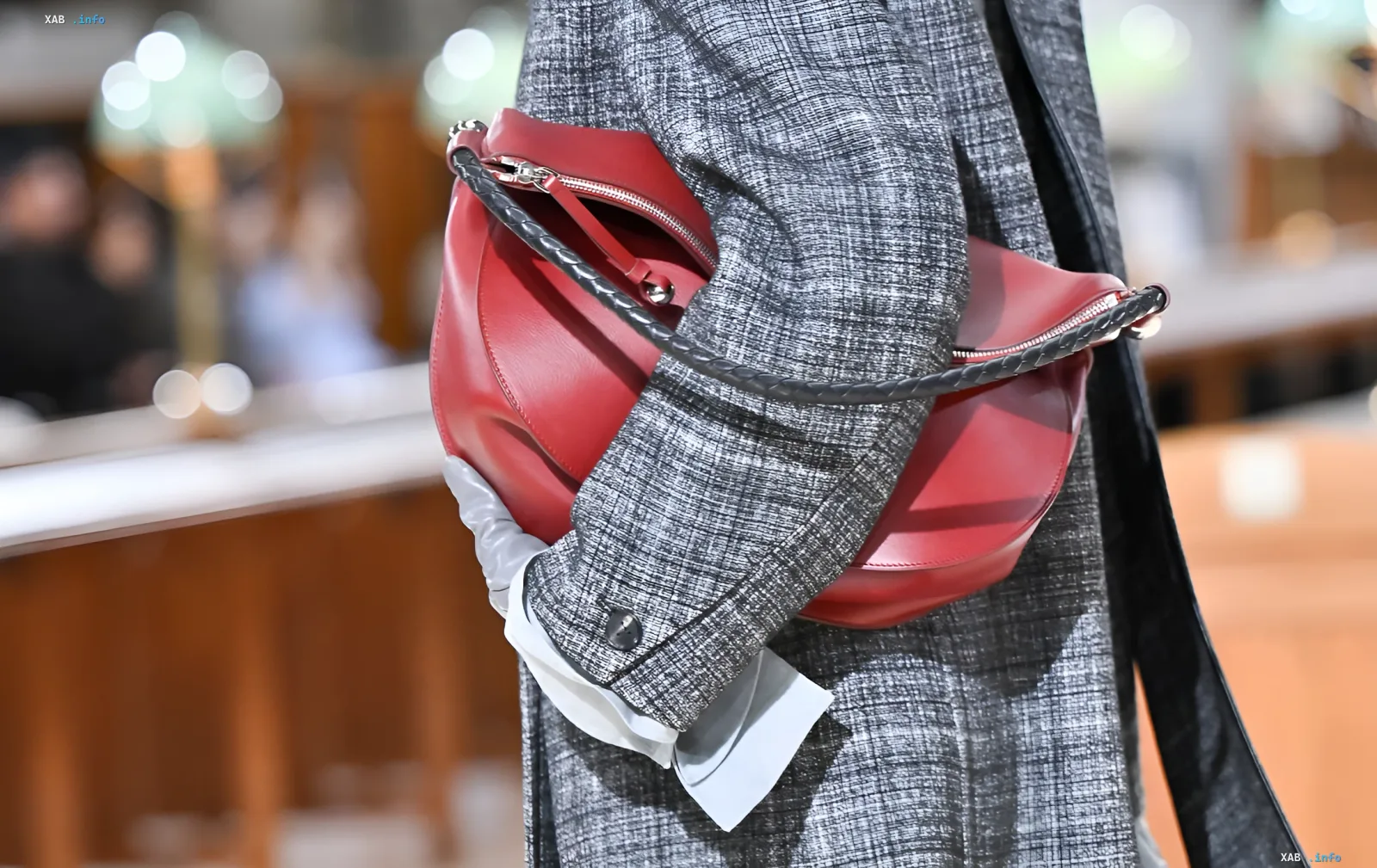 Große weiche burgunderfarbene Handtasche mit geflochtenem Henkel in den Händen eines Models auf der Laufsteg — Top-Accessoire-Trend für Herbst 2026