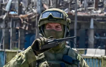 Russischer Soldat mit Taktikfunkgerät vor zerstörten Gebäuden bei Lyman, wo ISW und Milblogger einen russischen Rückzug bestätigten