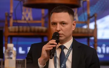 Redner im Anzug hält mit Mikrofon einen Vortrag auf einer Konferenz zur Wirtschaftssicherheit und Prävention wirtschaftlicher Risiken in der Ukraine