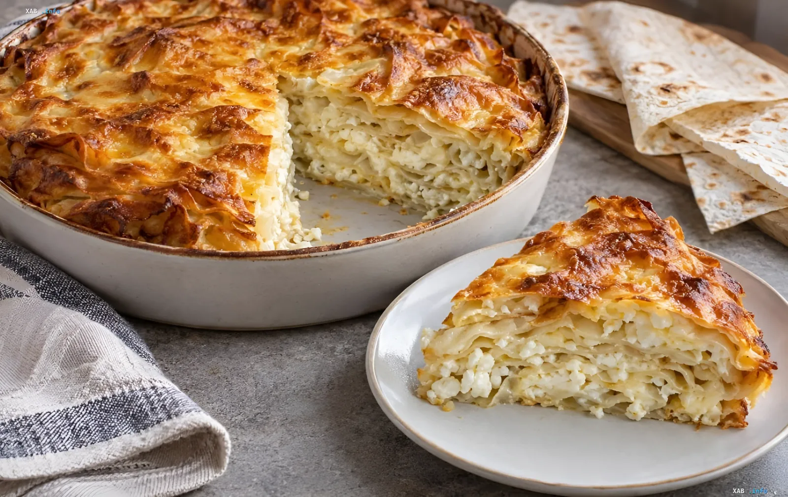 Faule Achma aus Lapha mit Sulguni-Käse und Quark — goldbrauner Auflauf in einer Form und auf einem Teller