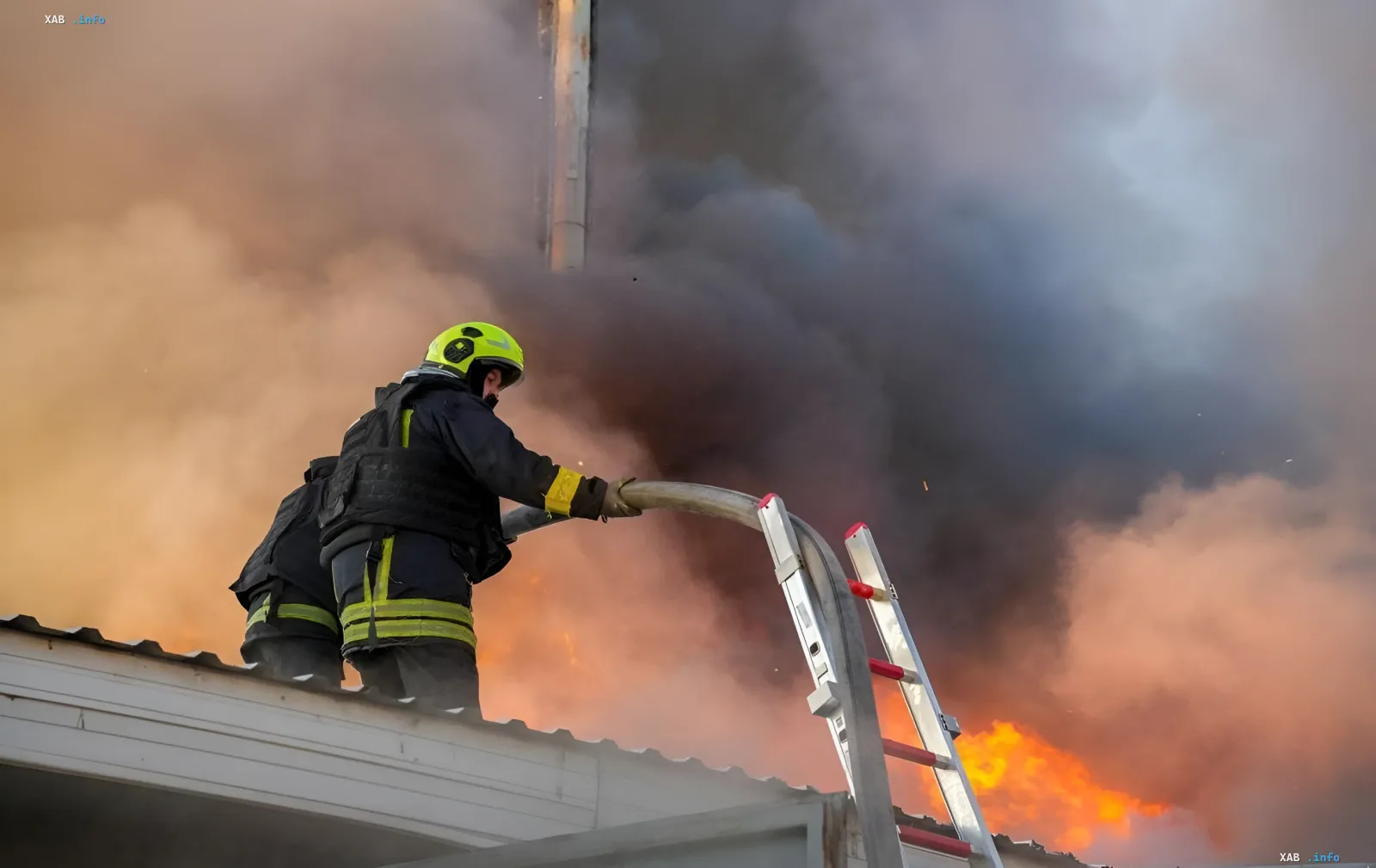 Feuerwehrmann löscht das Lager von Import-Office Ukraine nach dem Angriff: dichter Rauch und Flammen über dem Dach