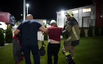 Спасатели выводят пострадавшего после обстрела логистического объекта в Одесской области ночью