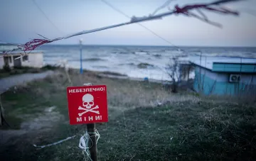 Warning sign reading 'Danger! Mines!' with a skull on a closed beach in Koblev where an anti-landing mine detonated