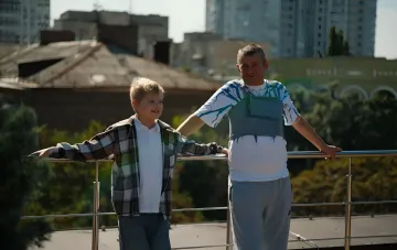 Пациент с искусственным сердцем и его сын на фоне города