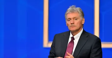 Spokesman in a dark suit with a burgundy tie against a blue screen backdrop comments on the Kremlin's rejection of a Putin-Zelensky meeting at the G20 in Miami