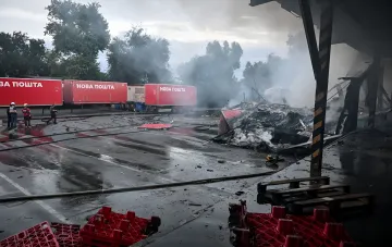 Aftermath of a Russian drone strike on a Nova Poshta terminal in Odesa region: smoke, burnt debris and Nova Poshta trucks