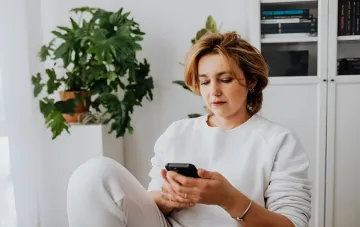 Frau wählt ein Android-Flaggschiff auf ihrem Smartphone aus und vergleicht Modelle unter 70.000 Hrywnja