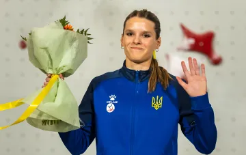 Polina Khalkovych in the Ukrainian national team jacket holding a bouquet after winning silver at the World Cup climbing stage in China