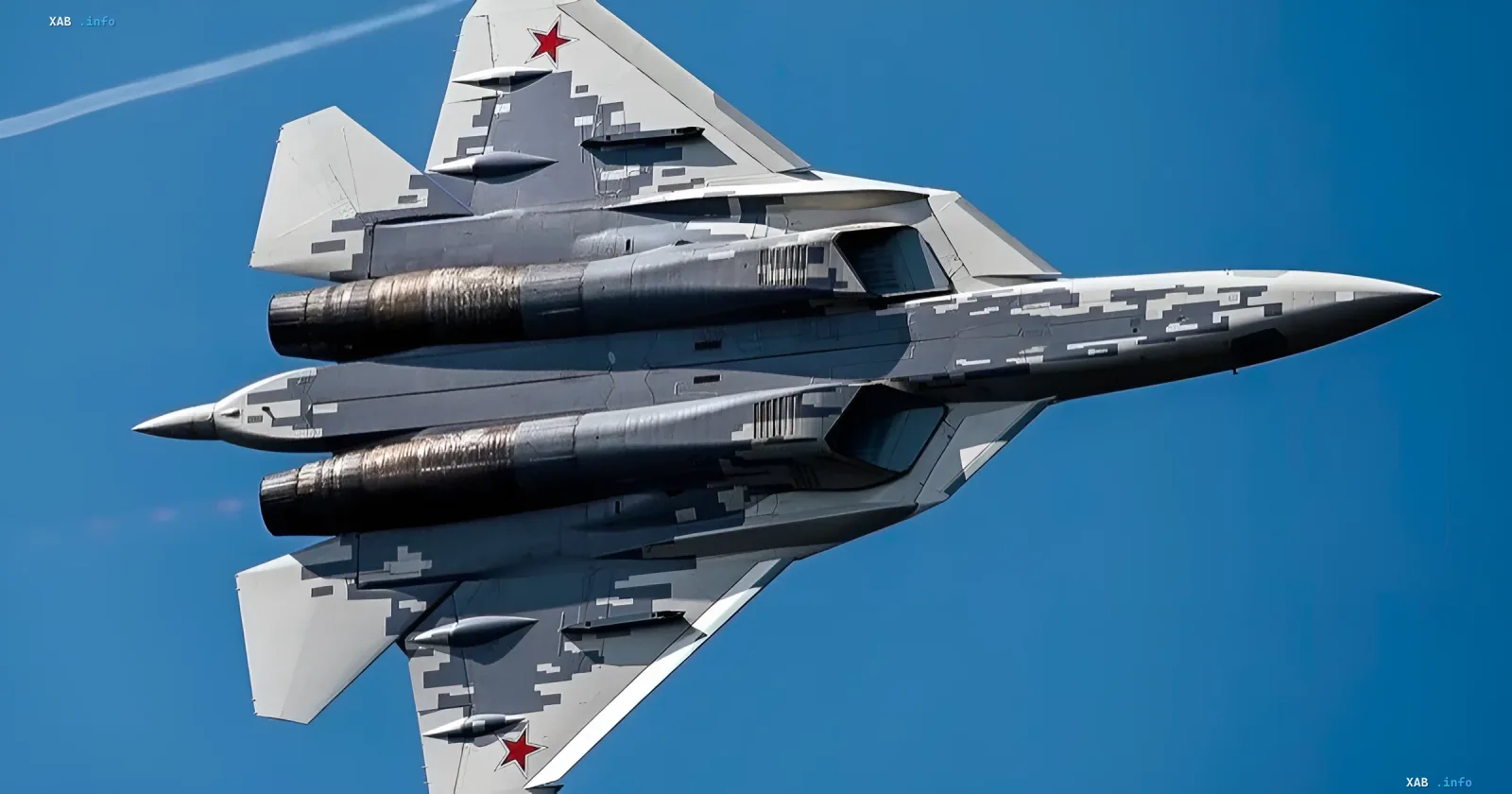 Літак п'ятого покоління Су-57 у польоті з цифровим камуфляжем і червоними зірками на крилах на тлі синього неба