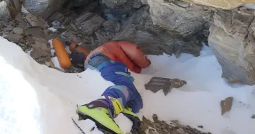 Body of an Indian mountaineer in bright green boots on Mount Everest snow, prepared for repatriation