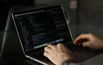 Розробник друкує код на ноутбуці під час роботи над проєктом в оновленому ChatGPT Sites від OpenAI