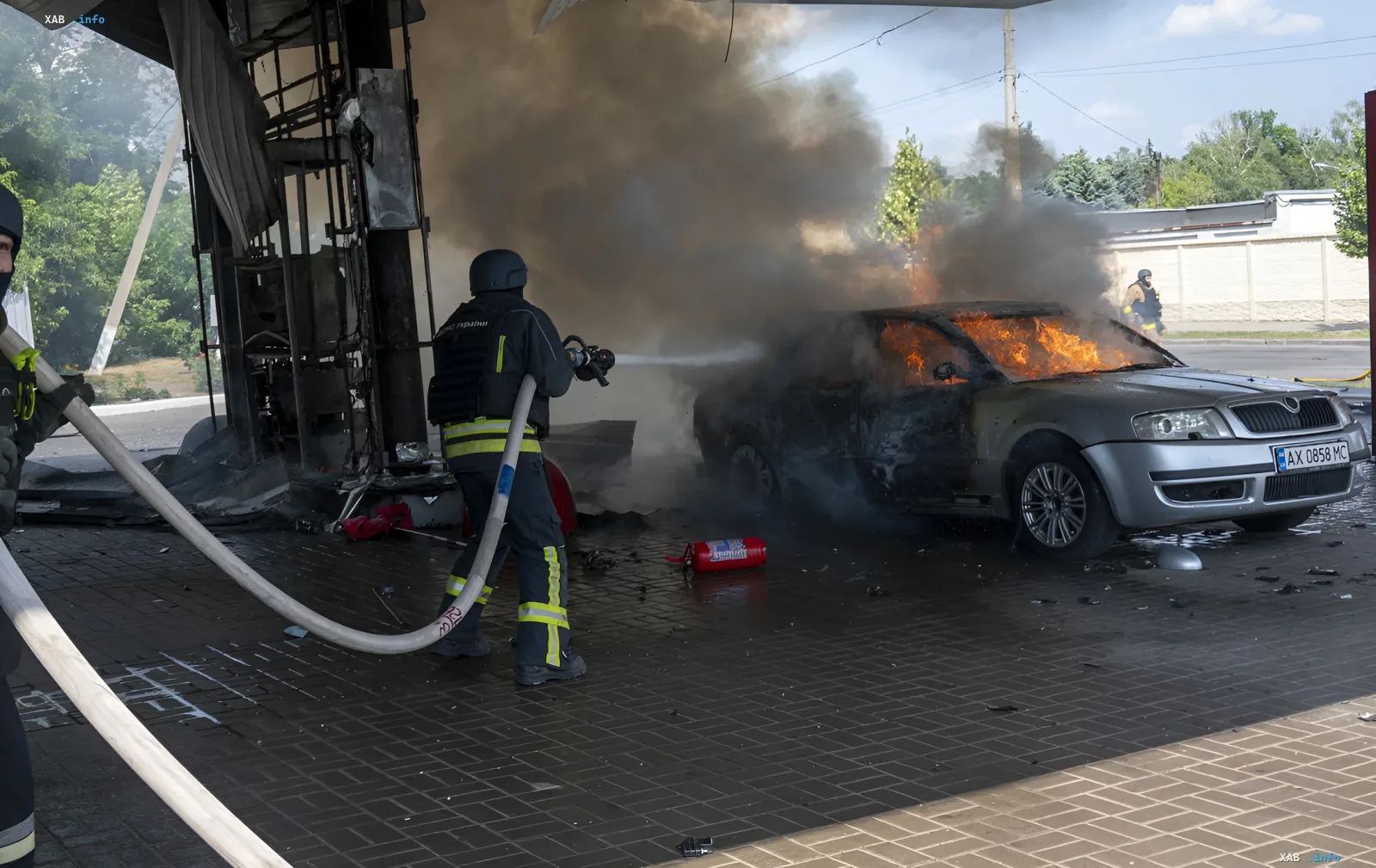 Firefighters extinguish a burning car next to a damaged building — aftermath of attacks on Ukraine's civilian infrastructure