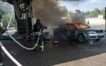 Пожарные тушат горящий автомобиль у повреждённого здания — последствия атак на гражданскую инфраструктуру Украины