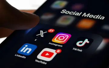 Пользователь открывает папку с приложениями Meta, TikTok, YouTube и X на смартфоне, чьи данные могут использоваться для обучения нейросетей