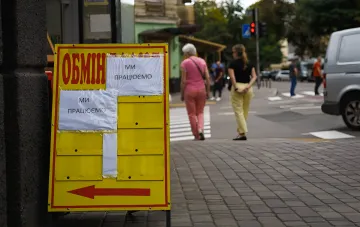 Жёлтое табло обменного пункта с курсами валют и надписью «Обмен» на городском тротуаре; актуальный курс доллара и евро в обменниках на 14 сентября