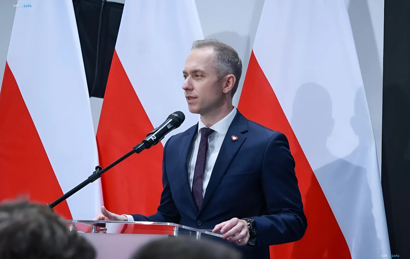 Польский представитель у трибуны с флагами Польши комментирует цели ударов РФ по западу Украины