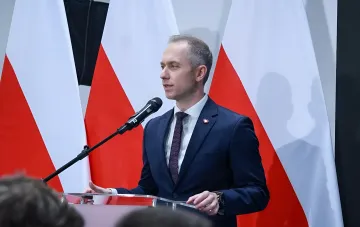 Польский представитель у трибуны с флагами Польши комментирует цели ударов РФ по западу Украины