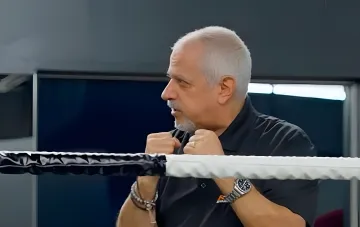 Рас Анбер, катмен Александра Усика, в боксёрской стойке у канатов ринга на фоне споров о месте боя Фьюри — Джошуа