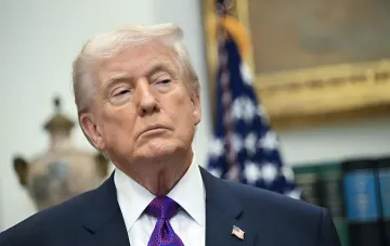 Дональд Трамп в костюме на фоне американского флага в контексте спора о выплатах $5000 и роли Конгресса