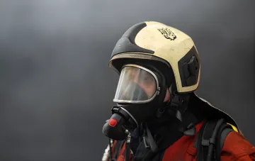 Firefighter in protective helmet and respirator at the scene of a Russian missile strike on Odesa, where the warehouse of pharmaceutical distributor BadM was hit