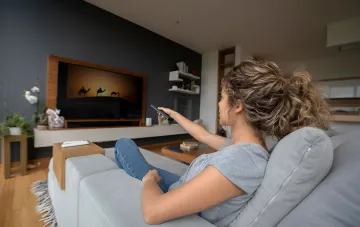 Woman watching a film with audio description on a home TV — accessible video content for blind viewers in Ukraine