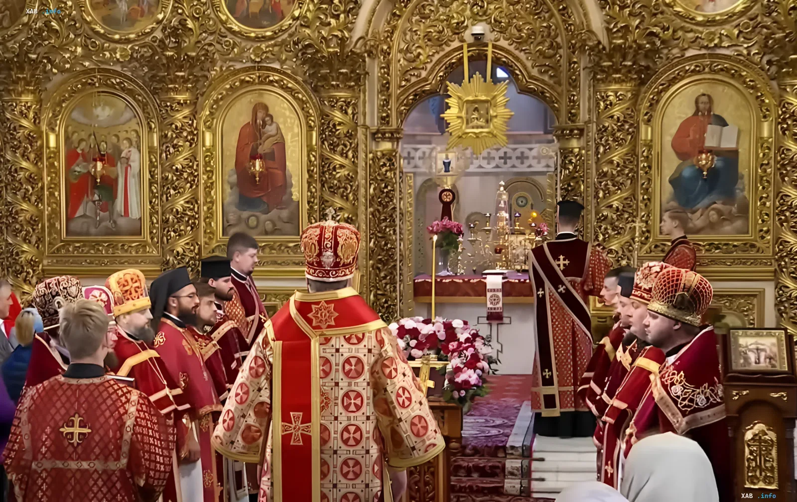 Богослужіння в храмі на свято Воздвиження Хреста Господнього: архиєрей у мітрі та священнослужителі в червоних одежах біля вівтаря з хрестом