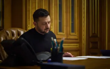 Ukrainian President Volodymyr Zelenskyy at his desk reviewing documents related to the dismissal of the Prosecutor General