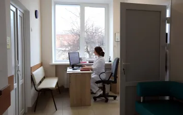Mediziner in weißem Kittel arbeitet am Computer im Büro, was den Personalmangel in der Medizin veranschaulicht