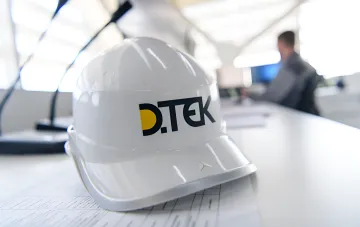 Білий будівельний шлем із логотипом ДТЭК на кресленнях: символ відновлення енергосистеми та рекордних проєктів компанії в умовах війни